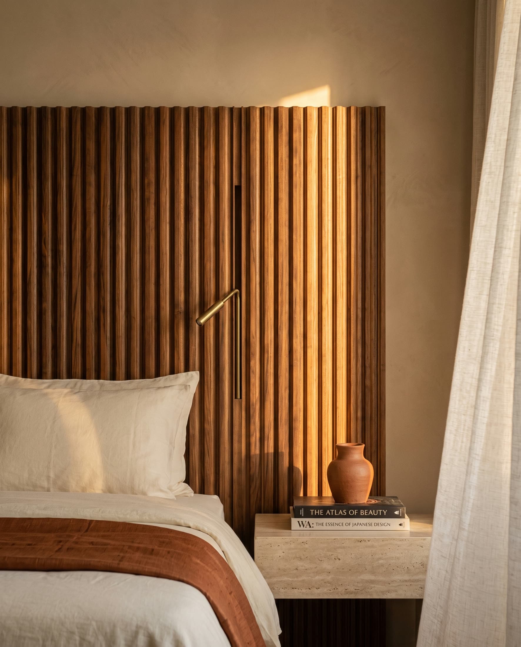 The fluted walnut headboard wall, lime plaster and brass of a principal bedroom